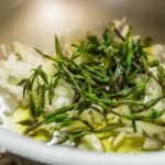 Soffriggere i germogli di luppolo selvatico con la cipolla