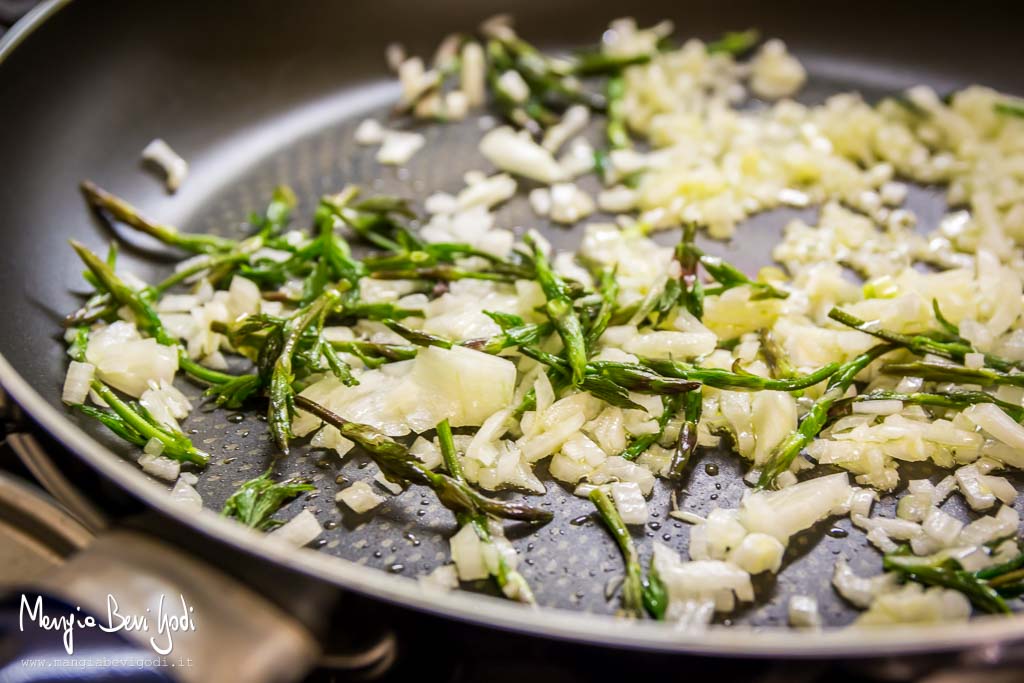 Soffriggere in padella la cipolla con i germogli di luppolo selvatico