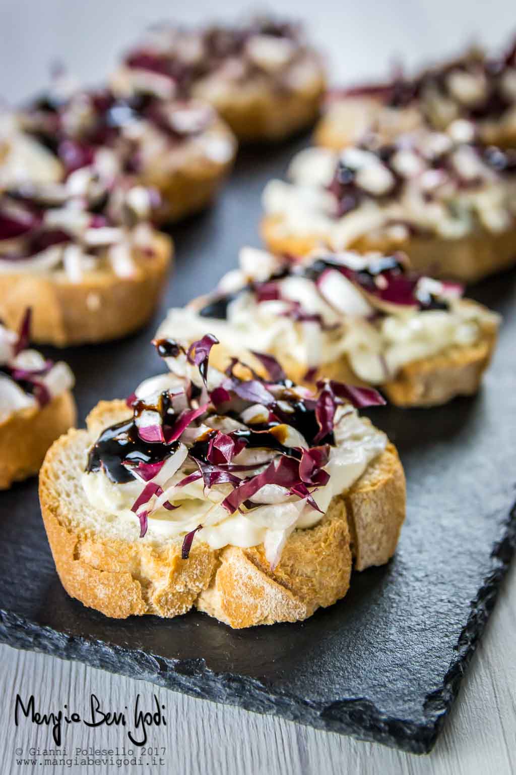 Crostini con radicchio di treviso e crema di gorgonzola e mascarpone, serviti su vassoio di ardesia