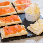 Crostini con salmone serviti su piatto di ardesia insieme a una ciotola di burro montato