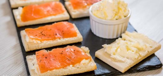 Crostini con salmone serviti su piatto di ardesia insieme a una ciotola di burro montato