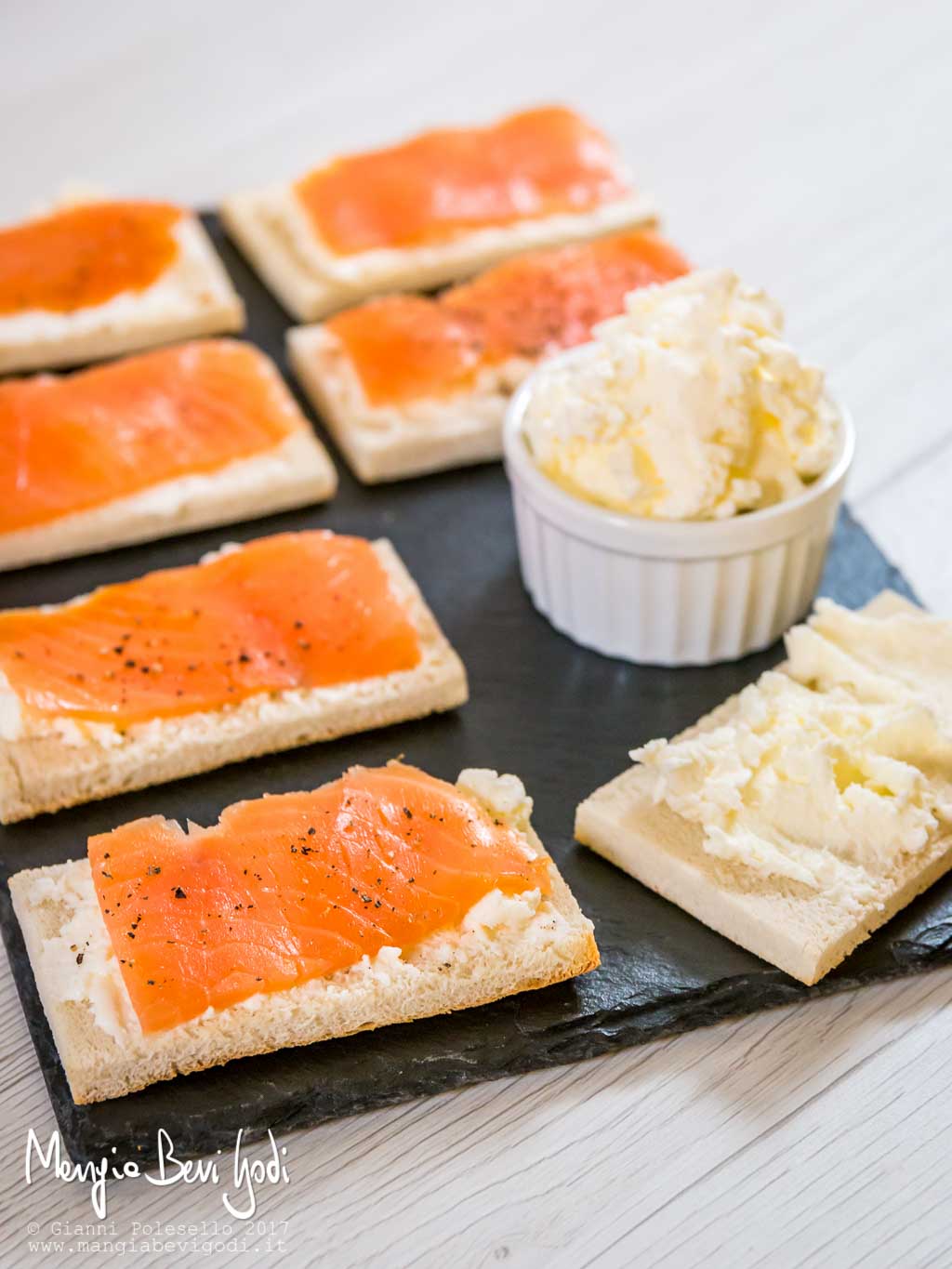 Crostini con salmone Crostini con salmone serviti su piatto di ardesia insieme a una ciotola di burro montato