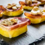 Antipasto di polenta, speck, provola e funghi sopra piatto di ardesia