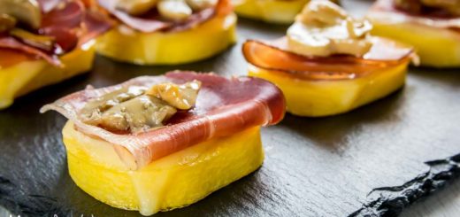 Antipasto di polenta, speck, provola e funghi sopra piatto di ardesia