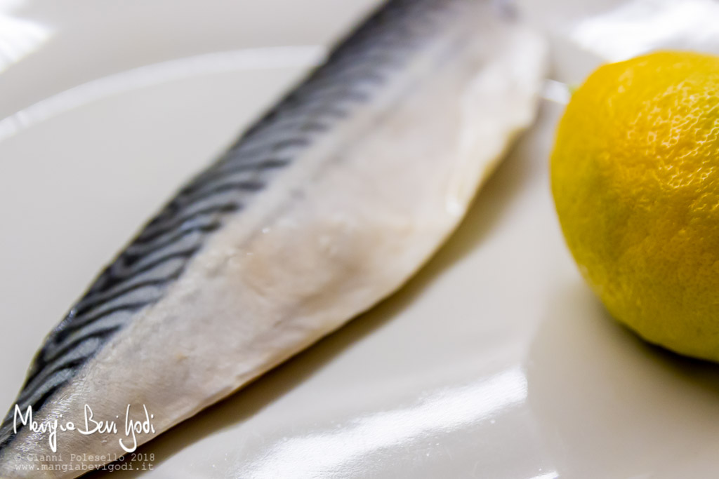 Filetto di sgombro e limone biologico su piatto in ceramica bianca