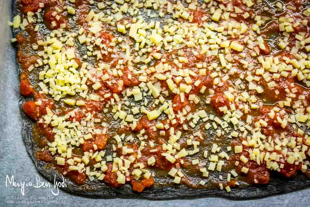 Pizza colorata con nero di seppia teglia ricoperta di carta da forno prima di essere infornata.