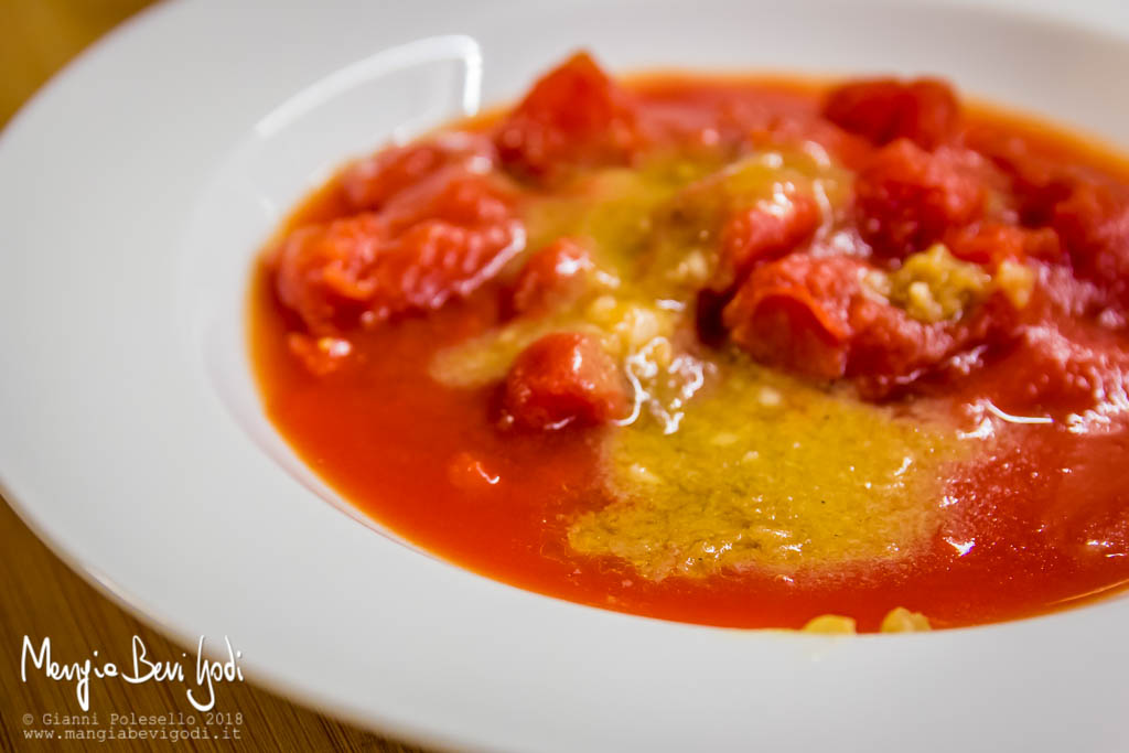 Polpa di pomodoro e fondo di cottura dei frutti di mare all'interno di un piatto fondo bianco