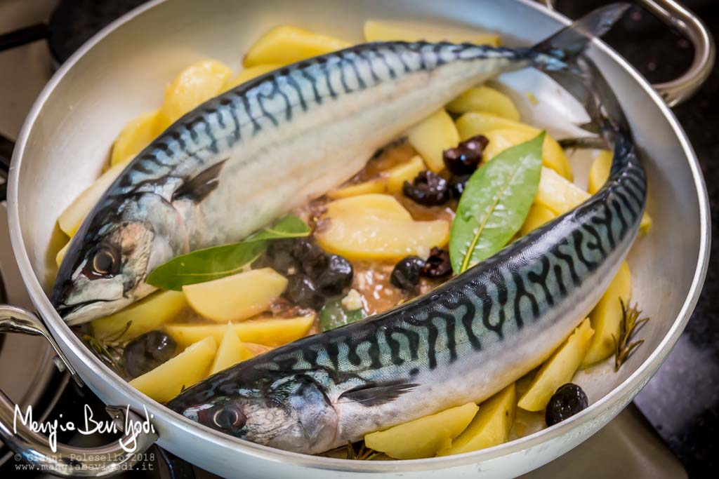 Cottura di due sgombri in padella di alluminio insieme a patate tagliate a spicchi, alloro, rosmarino e olive nere.