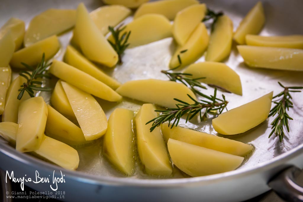 Cottura patate tagliate a spicchi e rosmarino in casseruola di alluminio