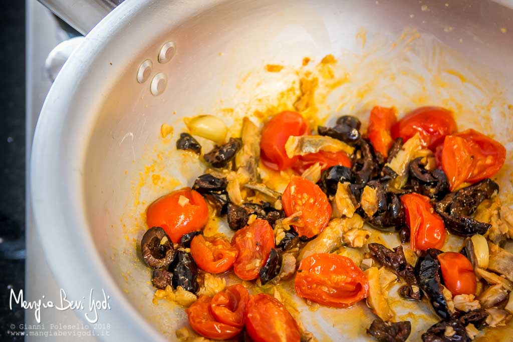 Preparazione sugo con aringa, pomodorini e olive nere in padella di alluminio