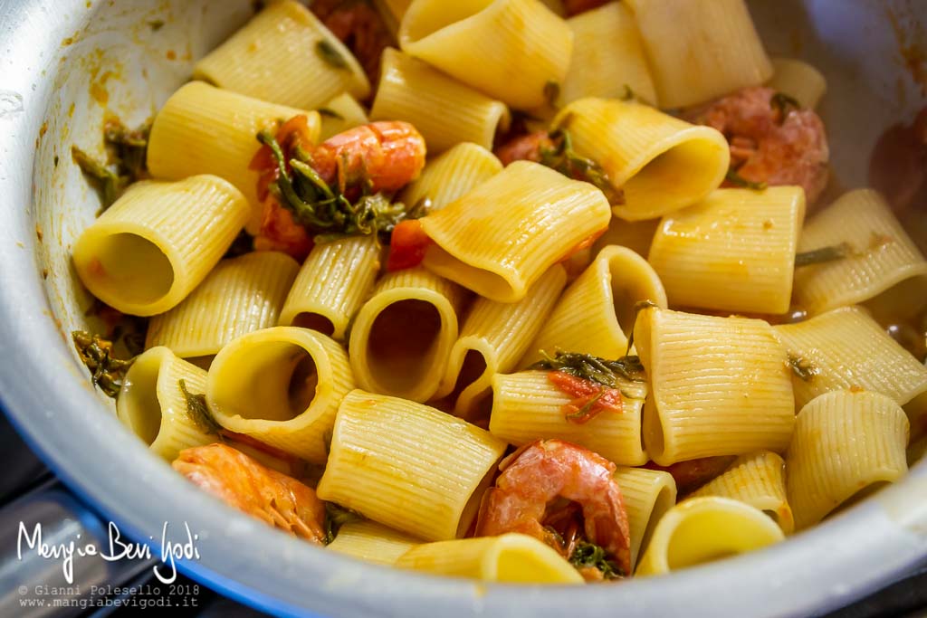 Spadellare i mezzi paccheri con il sugo di gamberoni, bruscandoli e pomodorini