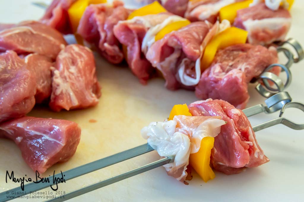 Cubetti di carne di vitello, quadrelli di peperone giallo e guanciale toscano infilati su due spiedini metallici.