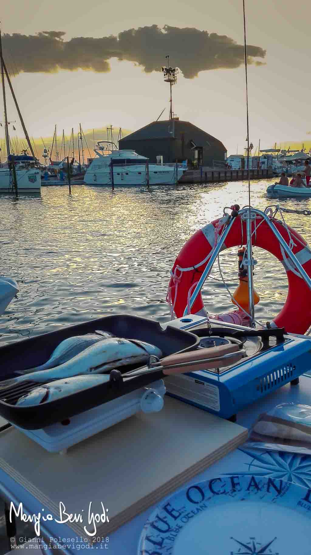 Orate alla griglia cotte in una bistecchiera nel pozzetto di una barca a vela al tramonto