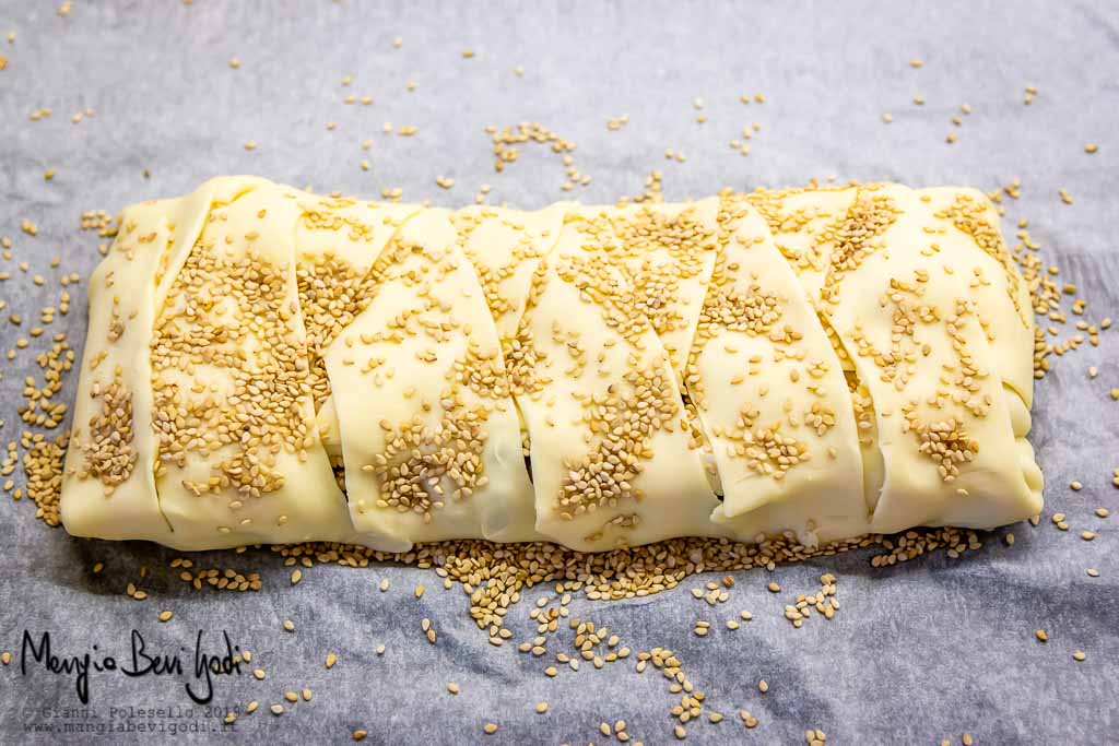 Comprimere i semi di sesamo sulla pasta sfoglia della torta