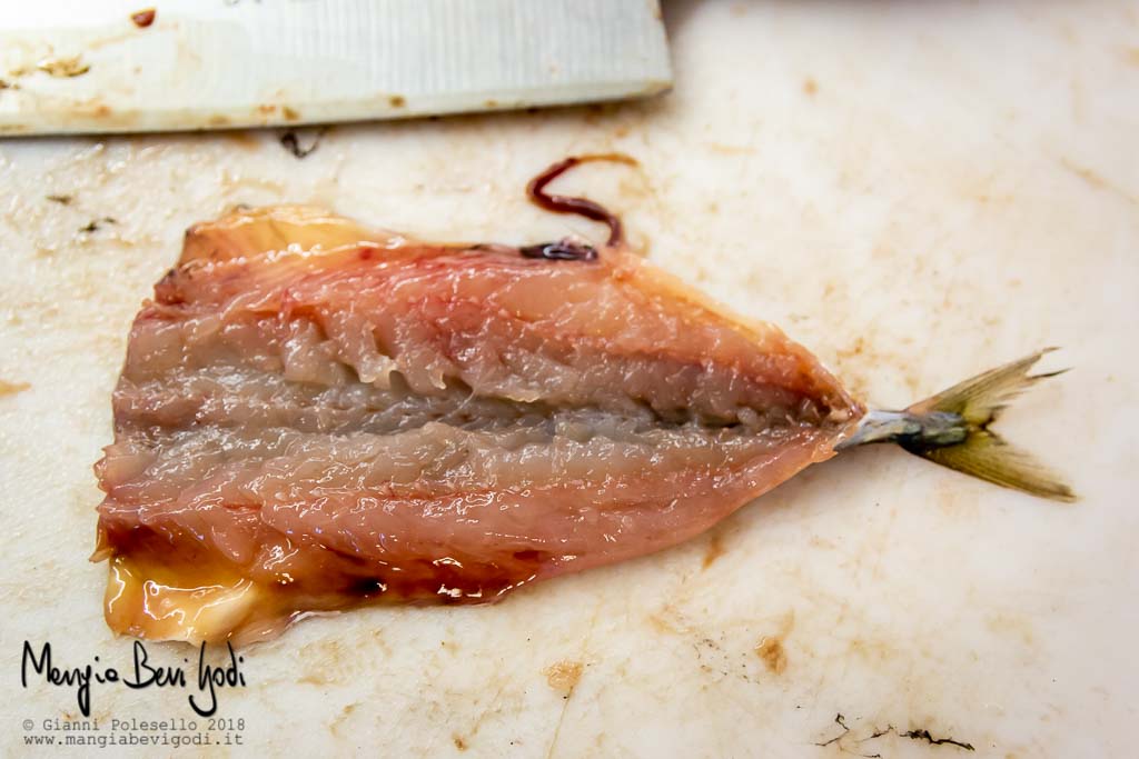 Pesce aperto a libro su tagliere bianco