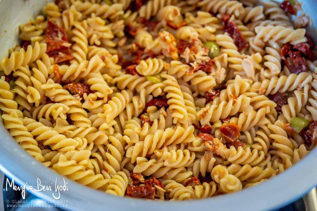 Spadellare la pasta con il sugo di pomodori secchi, tonno, olive e capperi.