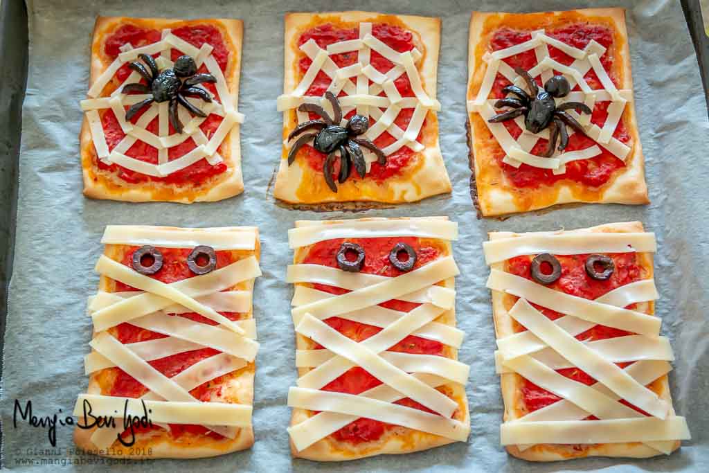 Teglia con pizzette decorate con ragni e mummie pronta da infornare