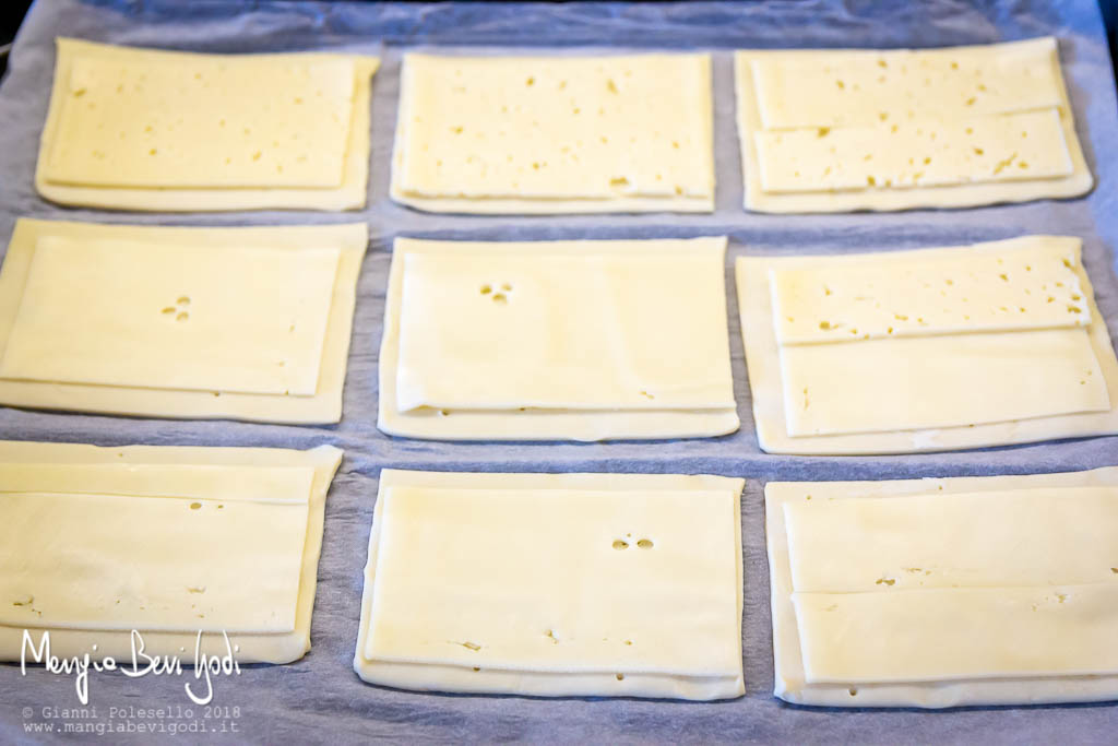 Disporre il formaggio a fette sopra i rettangoli di pasta sfoglia