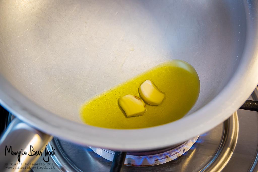 Spicchi d'aglio a soffriggere in padella di alluminio