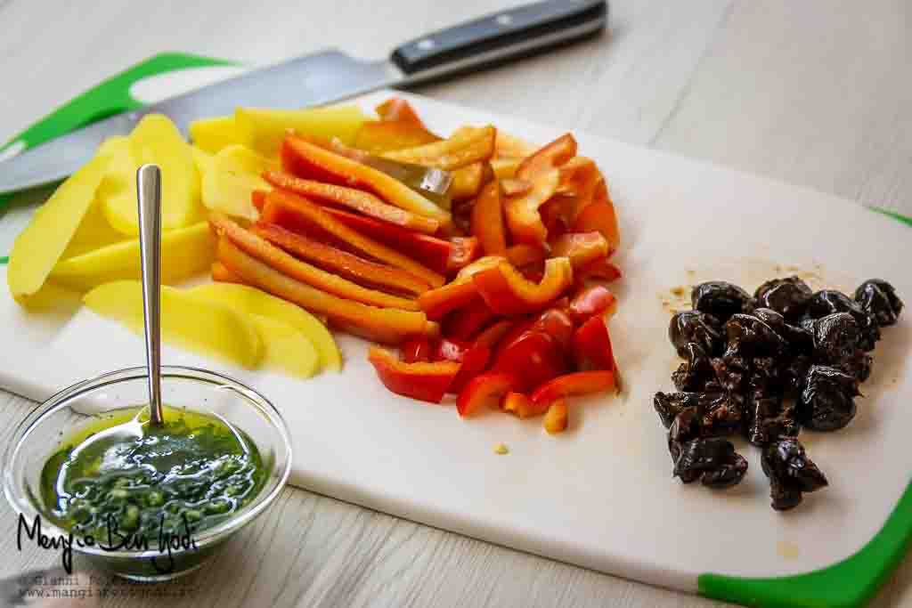 Tagliere con verdure (peperone, patata, olive) affettate e ciotola con emulsione di aglio, olio e prezzemolo