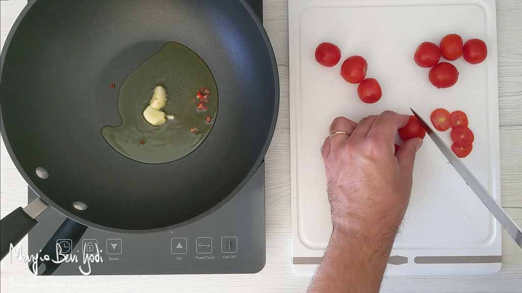 Soffriggere aglio e tagliare i pomodorini a metà