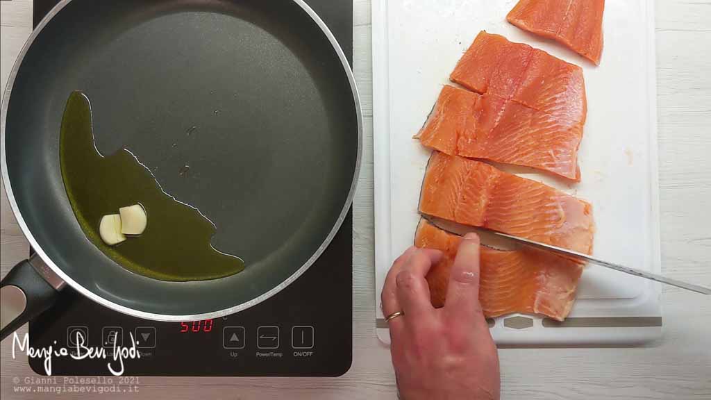 Soffriggere aglio e porzionare il filetto di trota