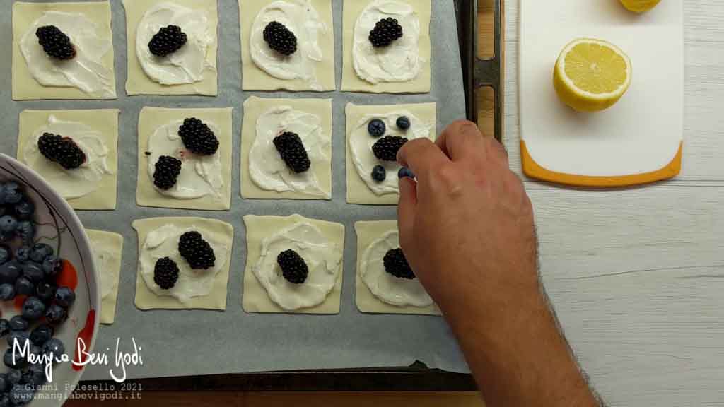 Posizionare i frutti di bosco sui quadrati di pasta sfoglia