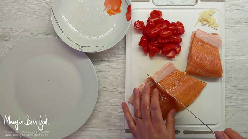 tagliare pomodorini, aglio e filetti di trota